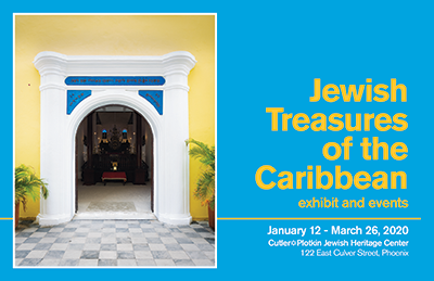 yellow stucco walls and small palm trees surround a door framed by white columns, opening into a dark synagogue